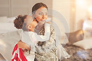 Adorable daughter giving her military mother a kiss