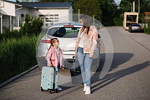 Adorable daughter with her mom go to airport with suitcases. Two girls goes to a trip. Little girl travel with mom.