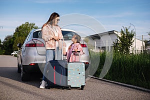 Adorable daughter with her mom go to airport with suitcases. Two girls goes to a trip. Little girl travel with mom.