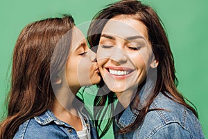 Adorable daughter kissing happy mother cheek isolated