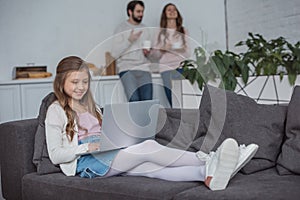 adorable daughter using laptop on sofa