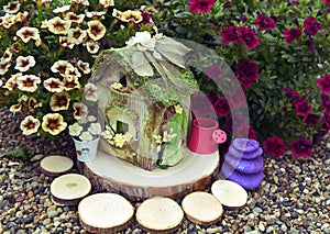 Adorable dollhouse with petunia flowers in the garden
