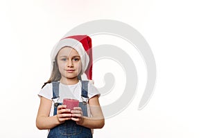 Adorable European baby girl in Santa hat with a lit red candle in hands, isolated over white background. Merry Christmas