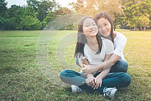 Adorable and Family Concept : Woman and child sitting relax on green grass. They hugging and feeling smiling happiness.