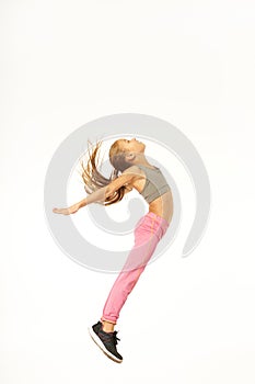 Adorable female child in sportswear jumping in studio