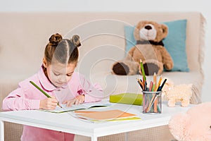 adorable focused child writing with pencil and studying