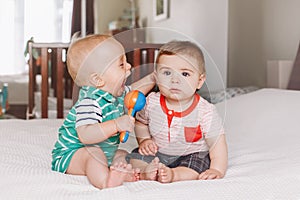 adorable funny baby boys sitting together on bed communicating and playing