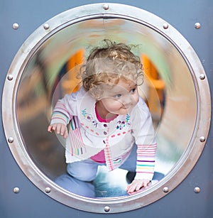 Adorable funny baby girl hiding on a playground