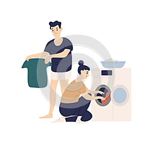 Adorable funny couple sorting clothes and putting it in washing machine. Cute smiling young man and woman doing laundry