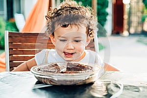 An adorable and funny little girl eats a cake in the yard