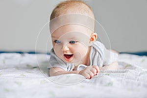 Adorable funny white Caucasian baby with blue eyes lying on tummy