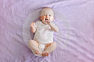 Adorable funny white Caucasian baby with blue eyes lying on tummy