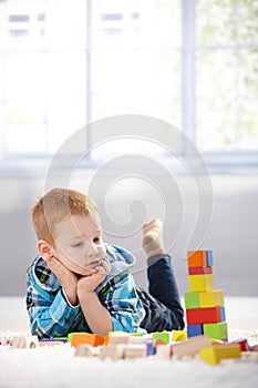 Adorable gingerish little boy with building cubes