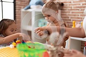 Adorable girl and boy playing with construction block pieces sitting on table at kindergarten