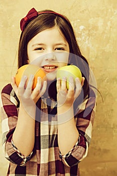 Adorable girl holding orange and apple in hands