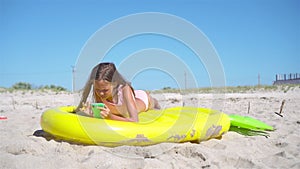 Adorable girl on inflatable air mattress on the beach