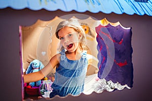 Adorable girl inside of carton playhouse