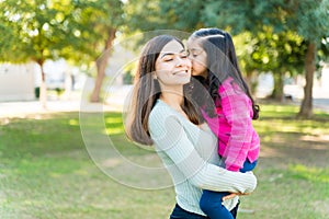 Adorable Girl Kissing Mother At Park