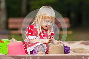 Adorable girl play with toys on sandbox