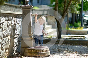 Adorable girl playing with drinking water fountain