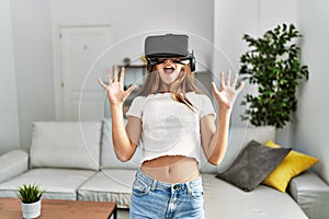 Adorable girl playing video game using vr goggles at home