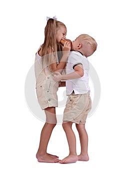 Girl and boy sharing a cinnamon bun isolated on a white background. Children eating a bun. Pastry production concept.