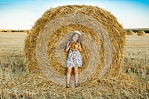 Adorable girl in rye field on sunset with a basket of bread