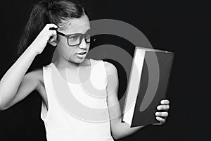 Adorable girl studying with eyeglasses and book in hand