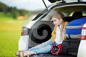 Adorable girl with a suitcase ready to go on vacations with her parents. Child looking forward for a road trip or travel. Autumn b