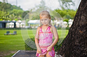Adorable girl take shower under tree at tropical beach resort