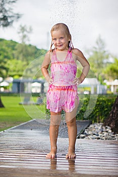 Adorable girl take shower under tree at tropical beach resort