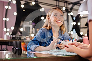 Adorable girl telling manicurist about desired nail color