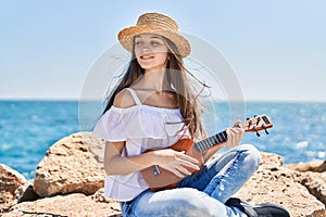 Adorable girl tourist smiling confident playing ukulele at seaside