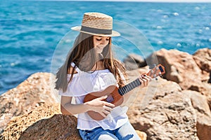 Adorable girl tourist smiling confident playing ukulele at seaside