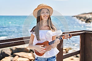 Adorable girl tourist smiling confident playing ukulele at seaside