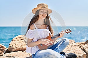 Adorable girl tourist smiling confident playing ukulele at seaside