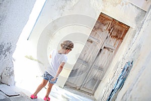 Adorable girl walking alone in narrow streets of