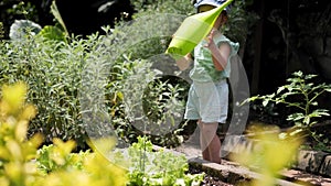 Adorable girl watering garden green plants with watering can