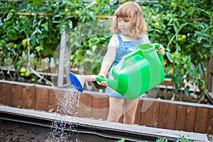 Adorable girl watering plants in the garden