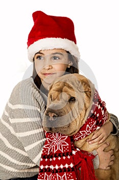 Adorable girl wearing a santa hat holding a Shar Pei dog