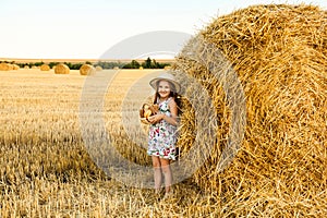 Adorable girl in rye field on sunset with a basket of bread