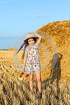 Adorable girl in rye field on sunset with a basket of bread