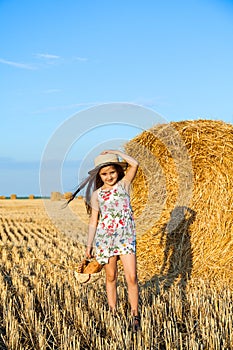 Adorable girl in rye field on sunset with a basket of bread