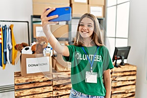 Adorable girl wearing volunteer uniform make selfie by the smartphone at charity center