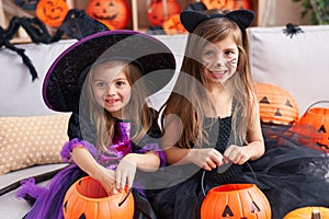 Adorable girls having halloween party holding pumpkin basket at home