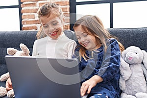 Adorable girls using laptop sitting on sofa at home