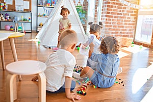 Adorable group of toddlers playing around lots of toys at kindergarten