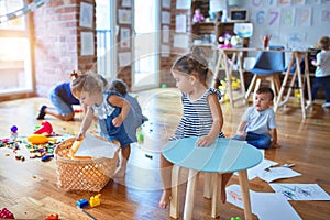 Adorable group of toddlers playing around lots of toys at kindergarten