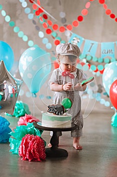 Adorable happy baby boy eating cake one at his first birthday cakesmash party