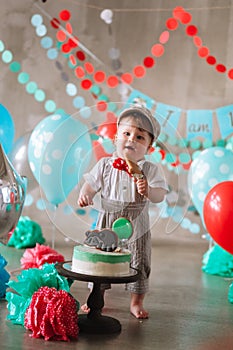 Adorable happy baby boy eating cake one at his first birthday cakesmash party